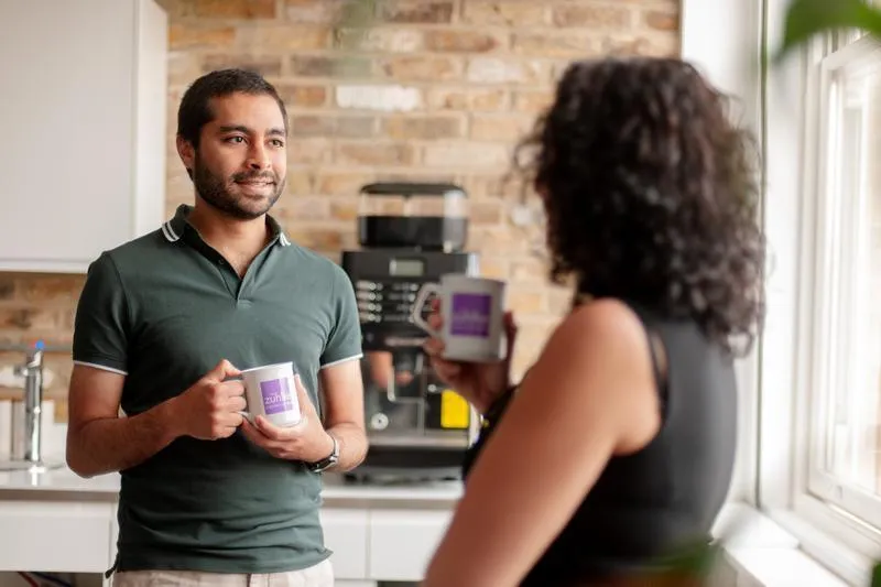 Mo talking to a woman in the office kitchen