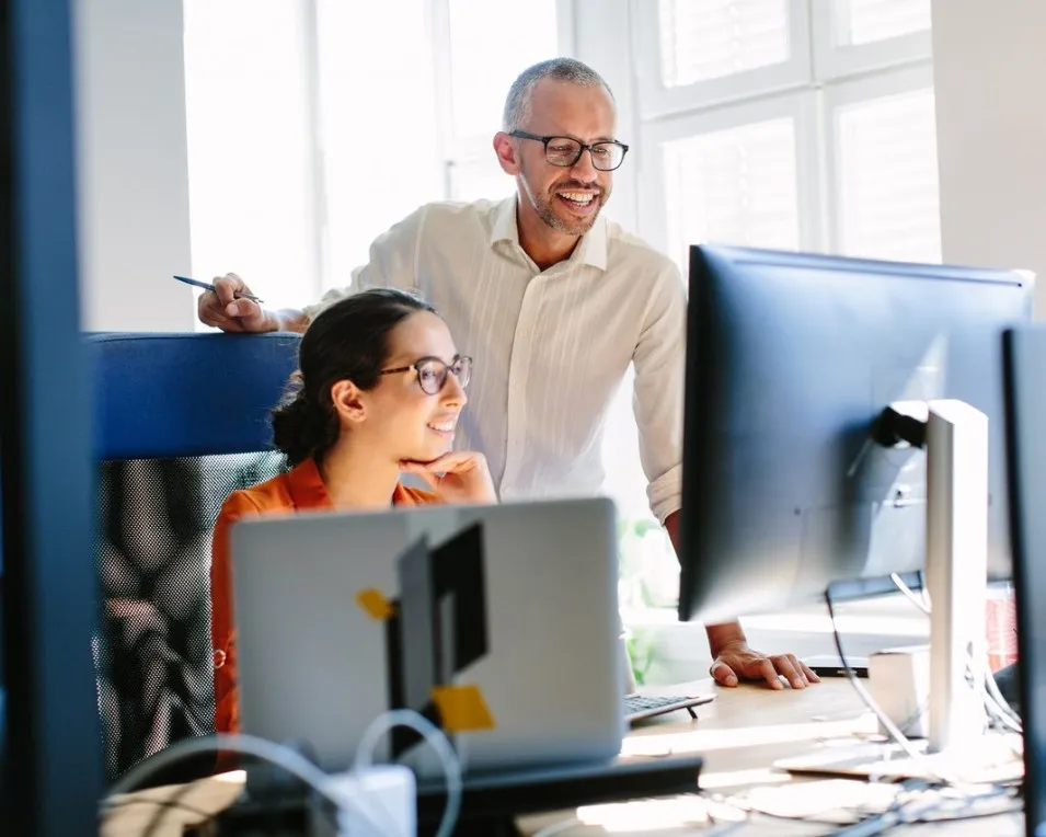 Two colleagues collaborating at a computer in a bright office, developing solutions for an AI accelerator project.