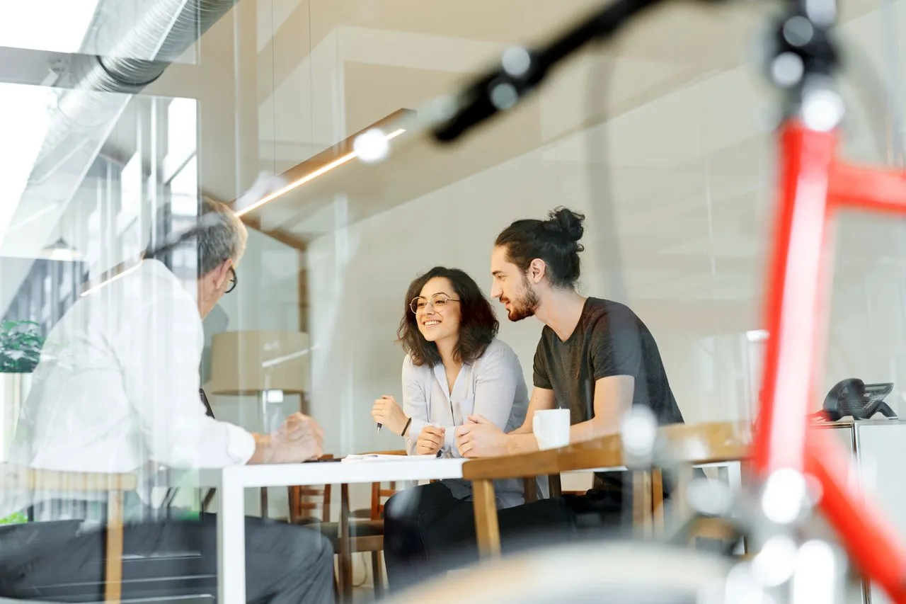 Three colleagues in a modern office discussing strategies for an AI accelerator programme.