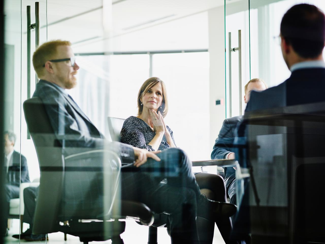 Female business executive listening to presentation by colleagues in office conference room