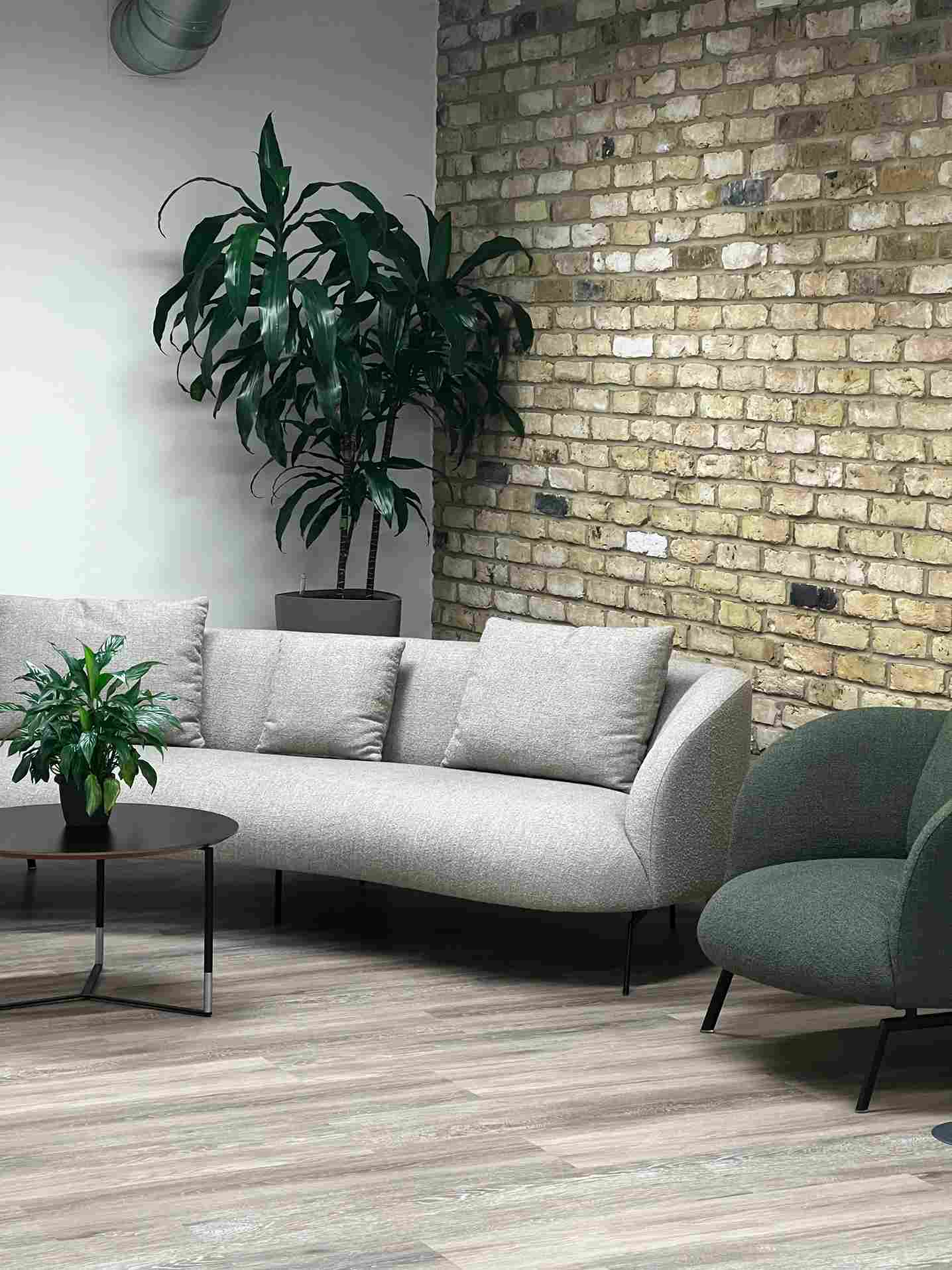 grey and dark green sofas surrounded by standing plants in Zühlke London office in Shoreditch