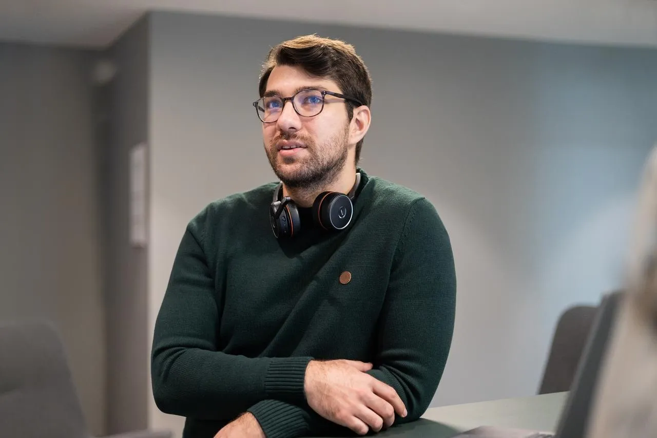 A man standing leaning on a standing desk in the office