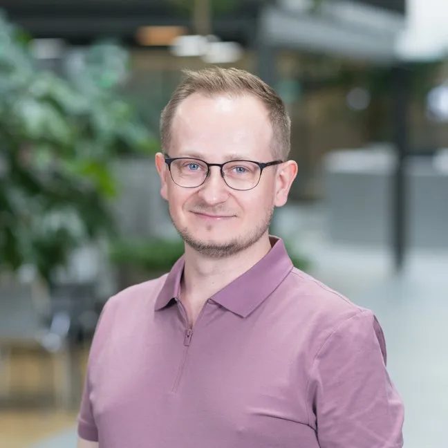 A portrait of a young man in glasses in the office setting