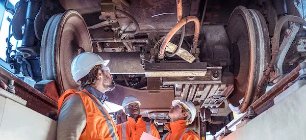 Mechanical engineers inspecting the underside of a car in a garage